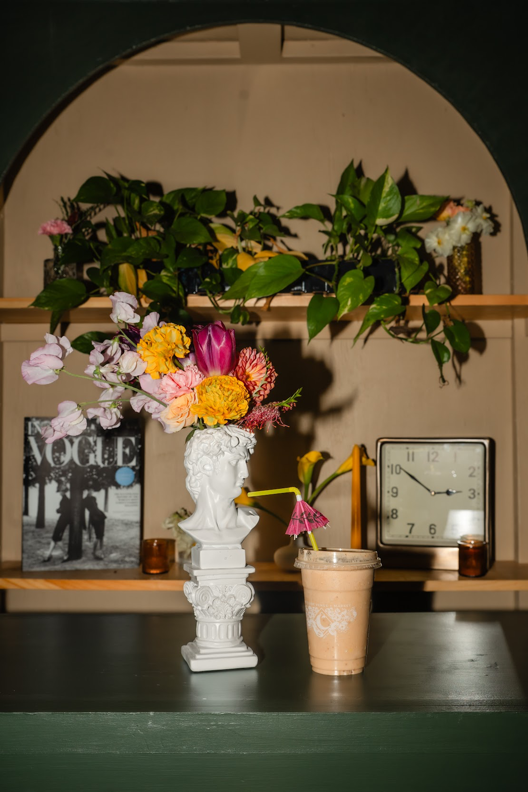 A creamy “Smoodie” smoothie blended with dates, banana, almond butter, and coconut milk. The drink has a thick texture and a rich, warm beige color, showcasing a naturally sweet and nutty flavor profile.