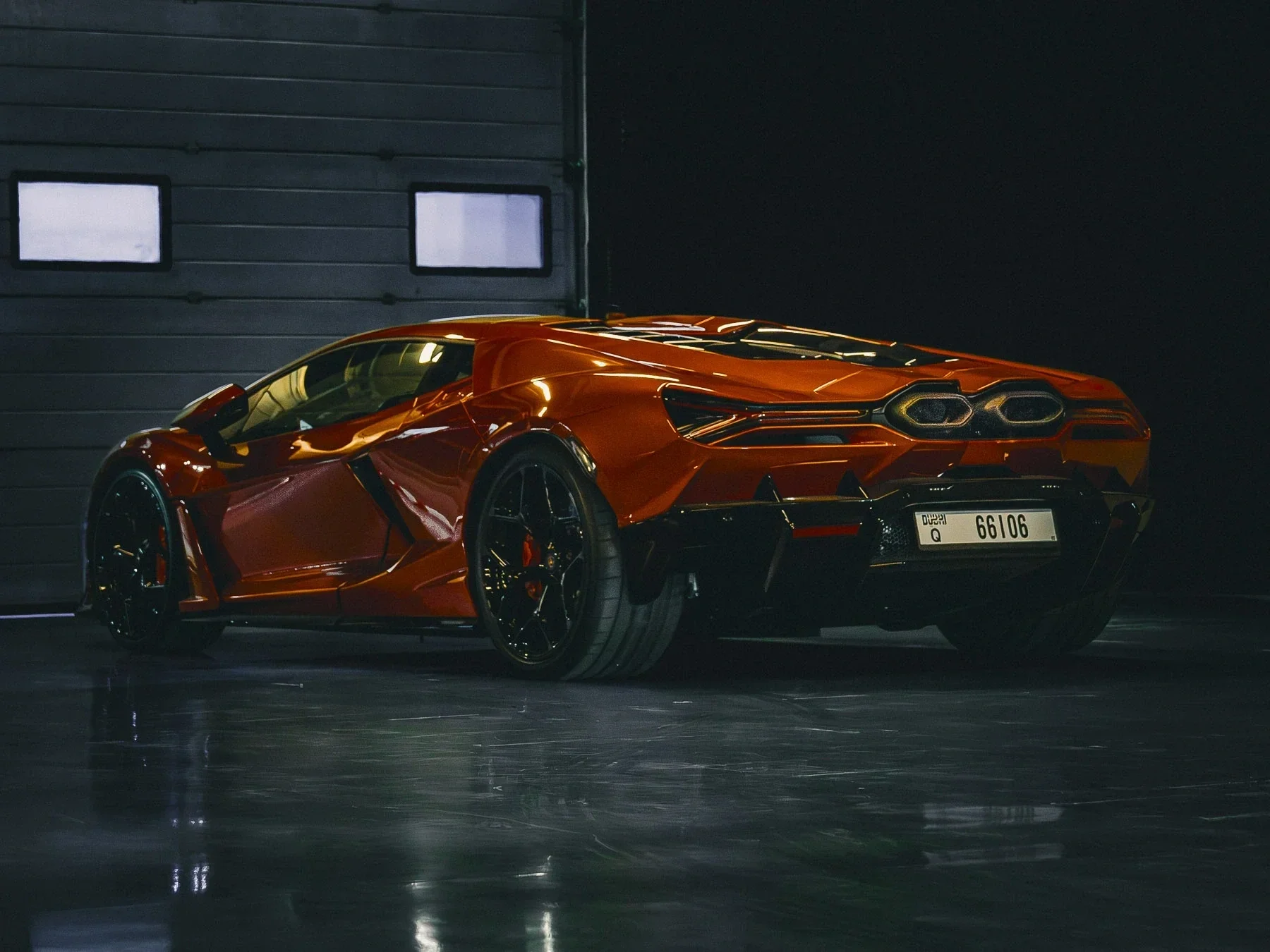 A red sports car in a garage with a dark background.