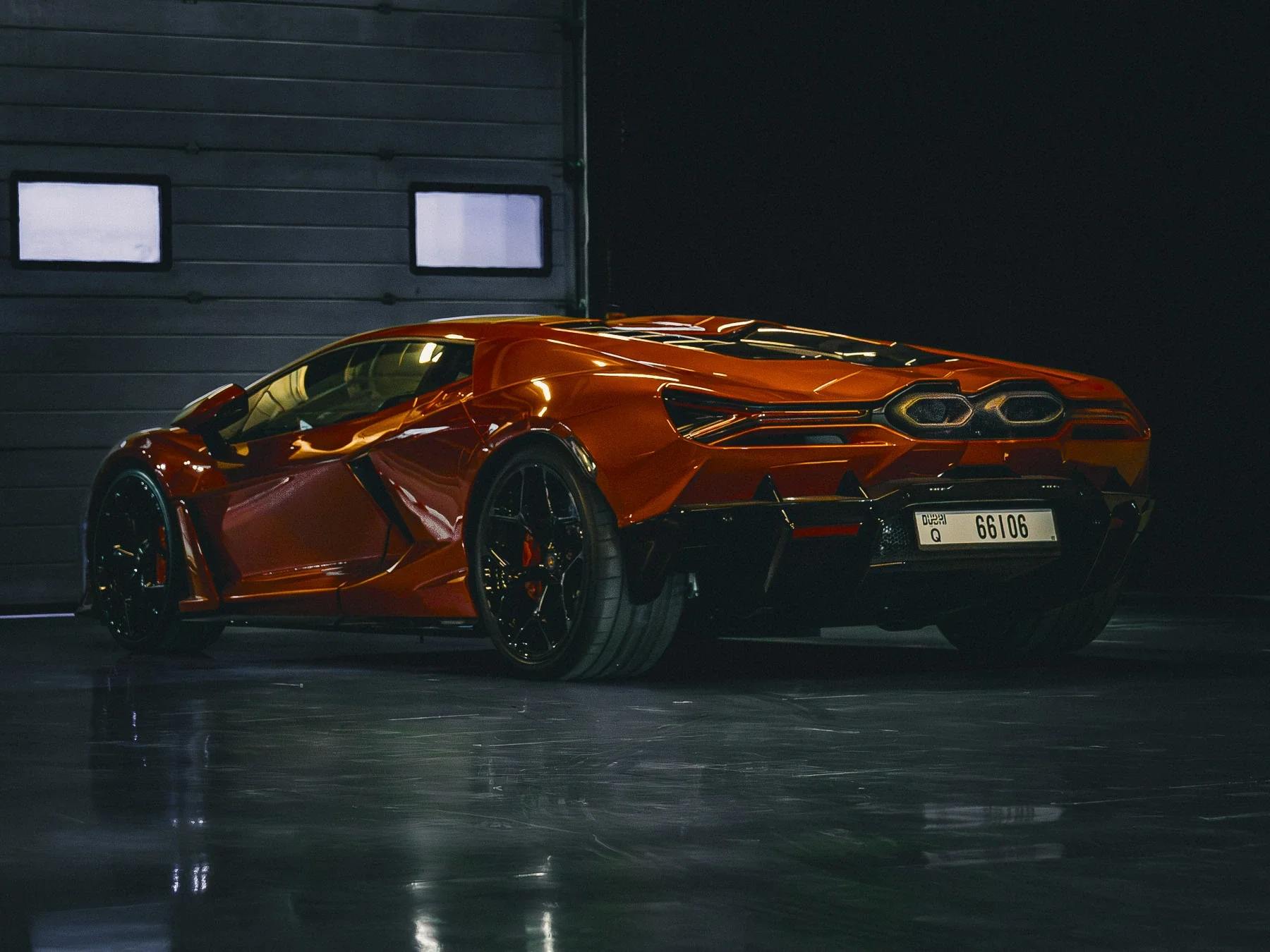 A red sports car in a garage with a dark background.