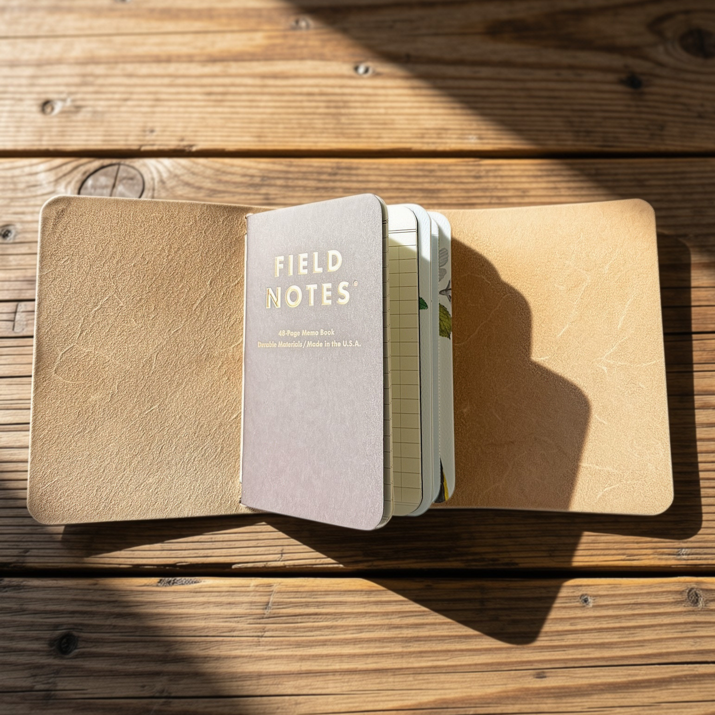 Natural suede Field Notes tri-fold cover with cord closure on a wood table, handmade by JAB Leatherworks