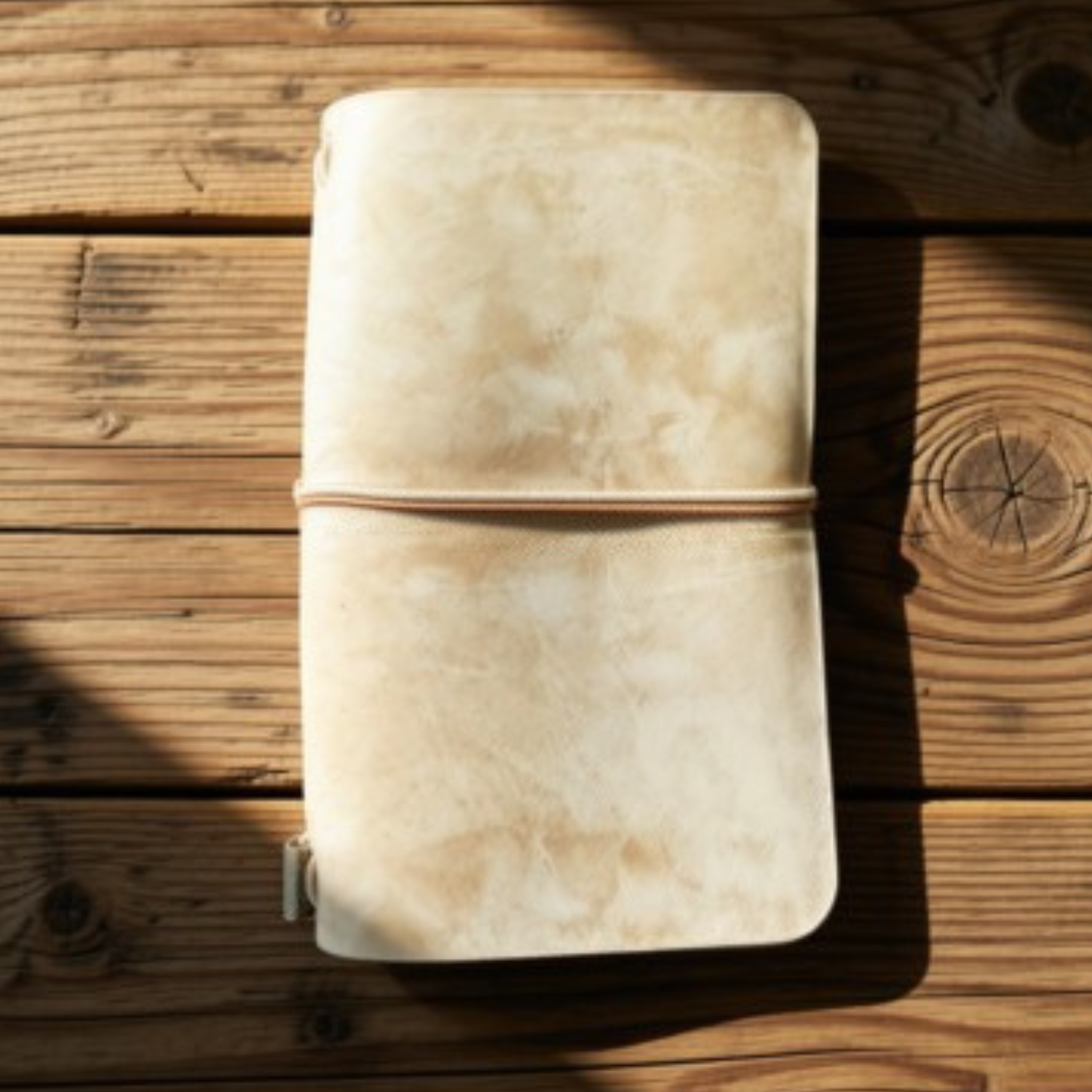 Natural suede Field Notes tri-fold cover with cord closure on a wood table, handmade by JAB Leatherworks