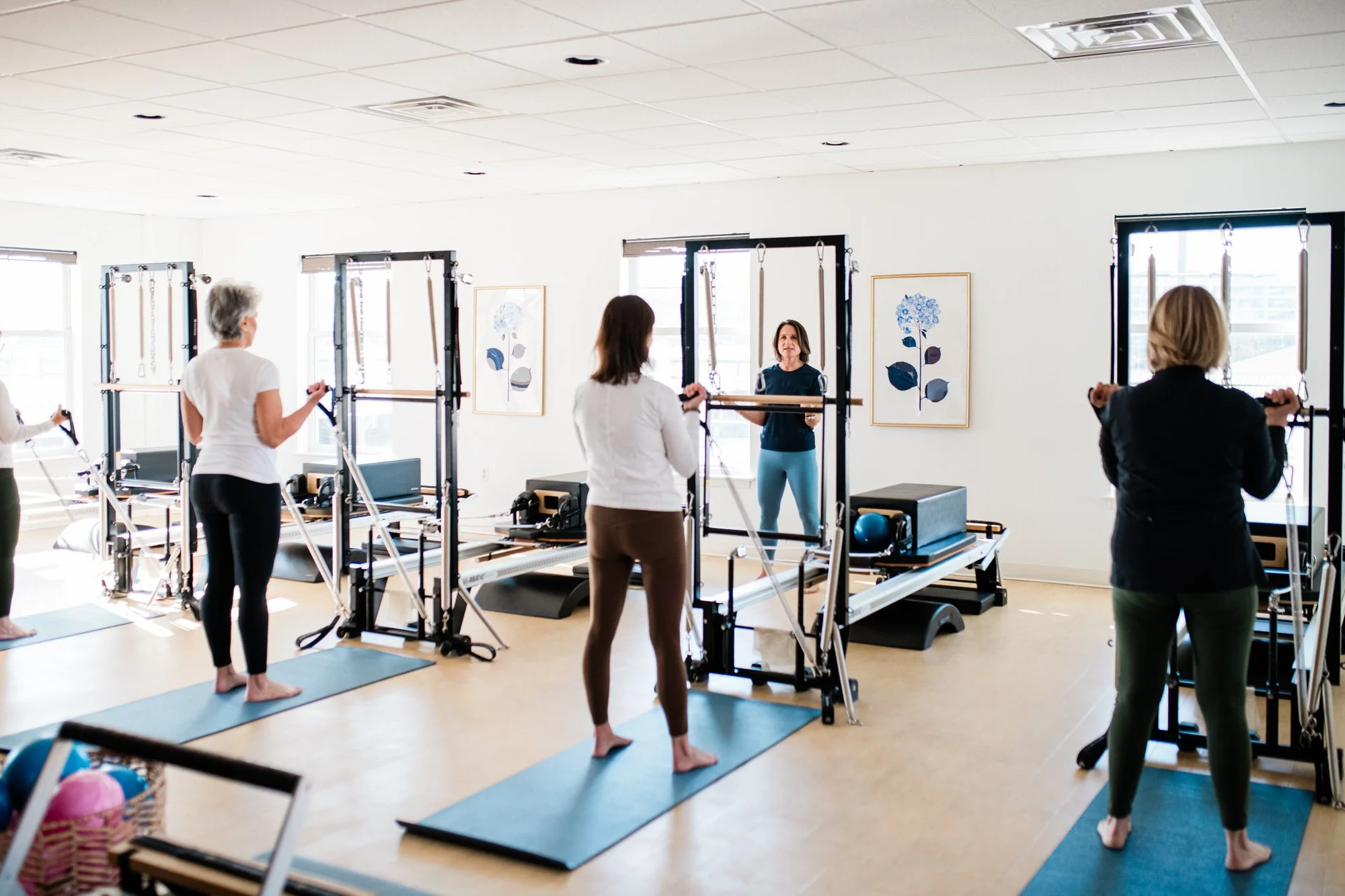 Women participating in a Pilates class using reformer machines at The Pilates Place in Timonium, MD
