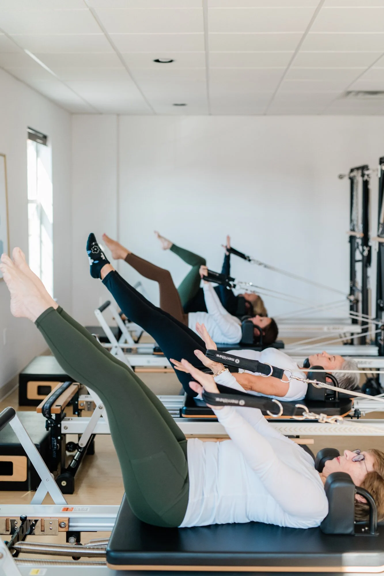 People exercising on Pilates reformers in a fitness class at The Pilates Place in Timonium, MD