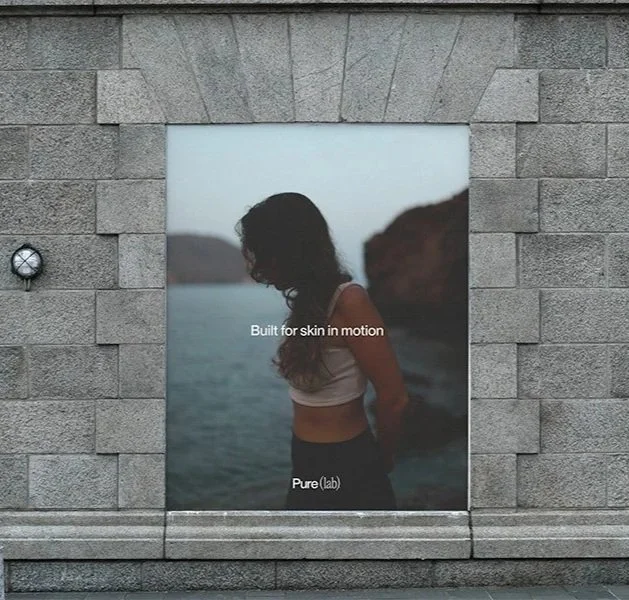 Werbetafel mit einem Bild einer Frau am Wasser, die von einer Felsenwand im Hintergrund umgeben ist, mit Text "Built for skin in motion" und "Purelab"
