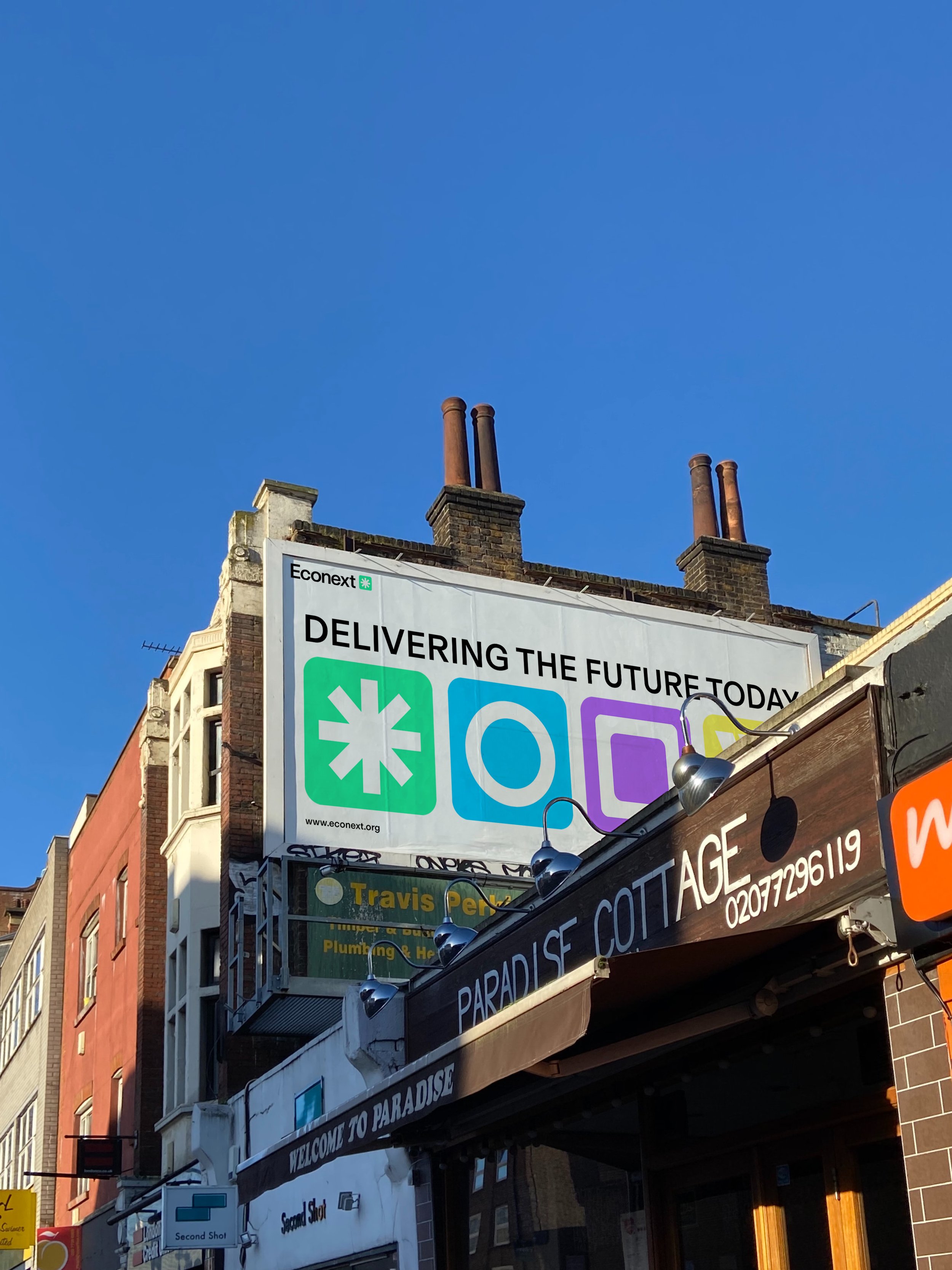Mehrere Werbetafeln und Schilder an einer Straßenseite in einer Stadt. Das größte Schild enthält das Logo von EcoNext und den Satz „Delivering the Future Today“.