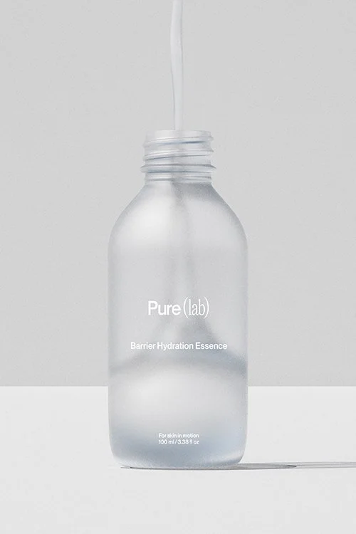 Ein透明 Flasche mit weißem Inhalt und einer aufgeschraubten Pipette, die Flüssigkeit in die Flasche tropft, auf grauem Hintergrund.