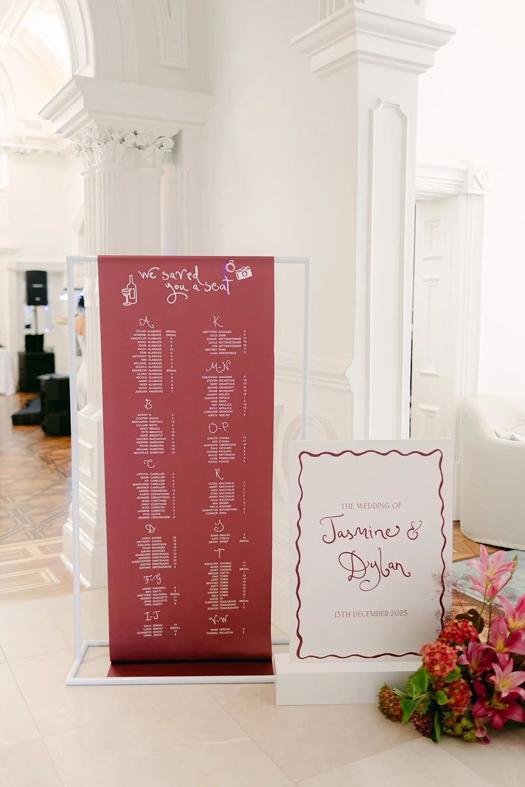 Satin seating chart beside a floral installation for a wedding reception at Quat Quatta
