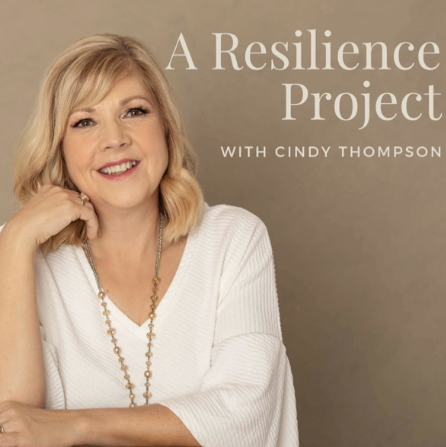 A Reslience Project podcast artwork. Cindy Thompson in a white v neck blouse with a long gold necklace against a neutral background.