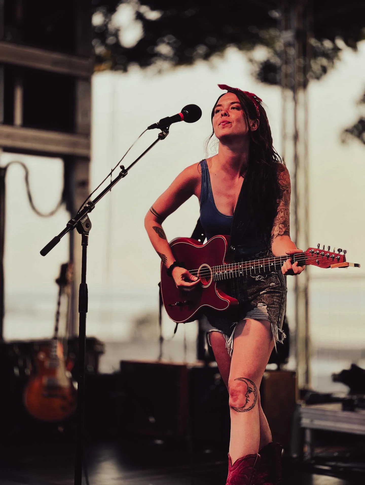 Photo of Savanna Woods on stage playing guitar.