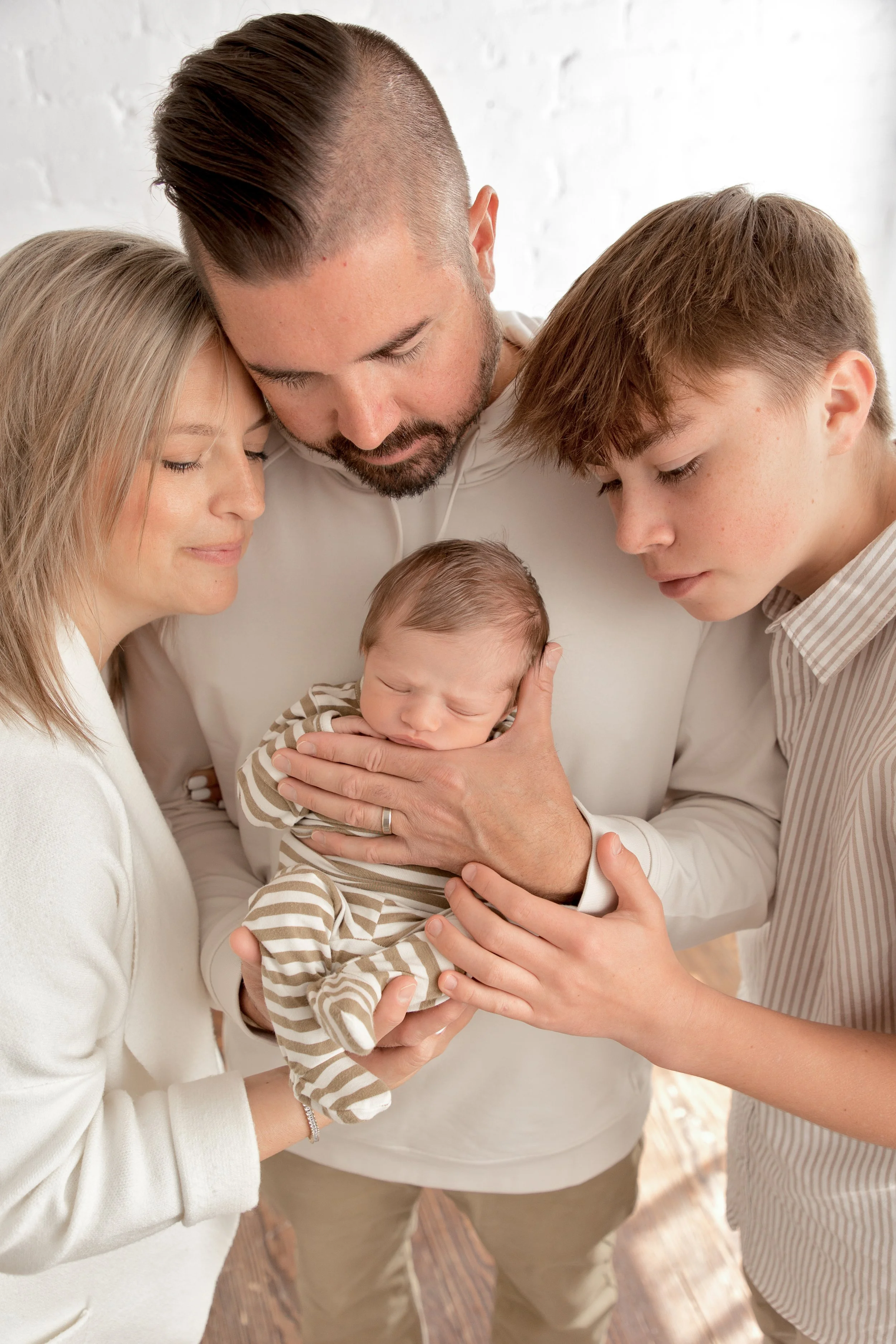 family gathers around sleeping newborn baby