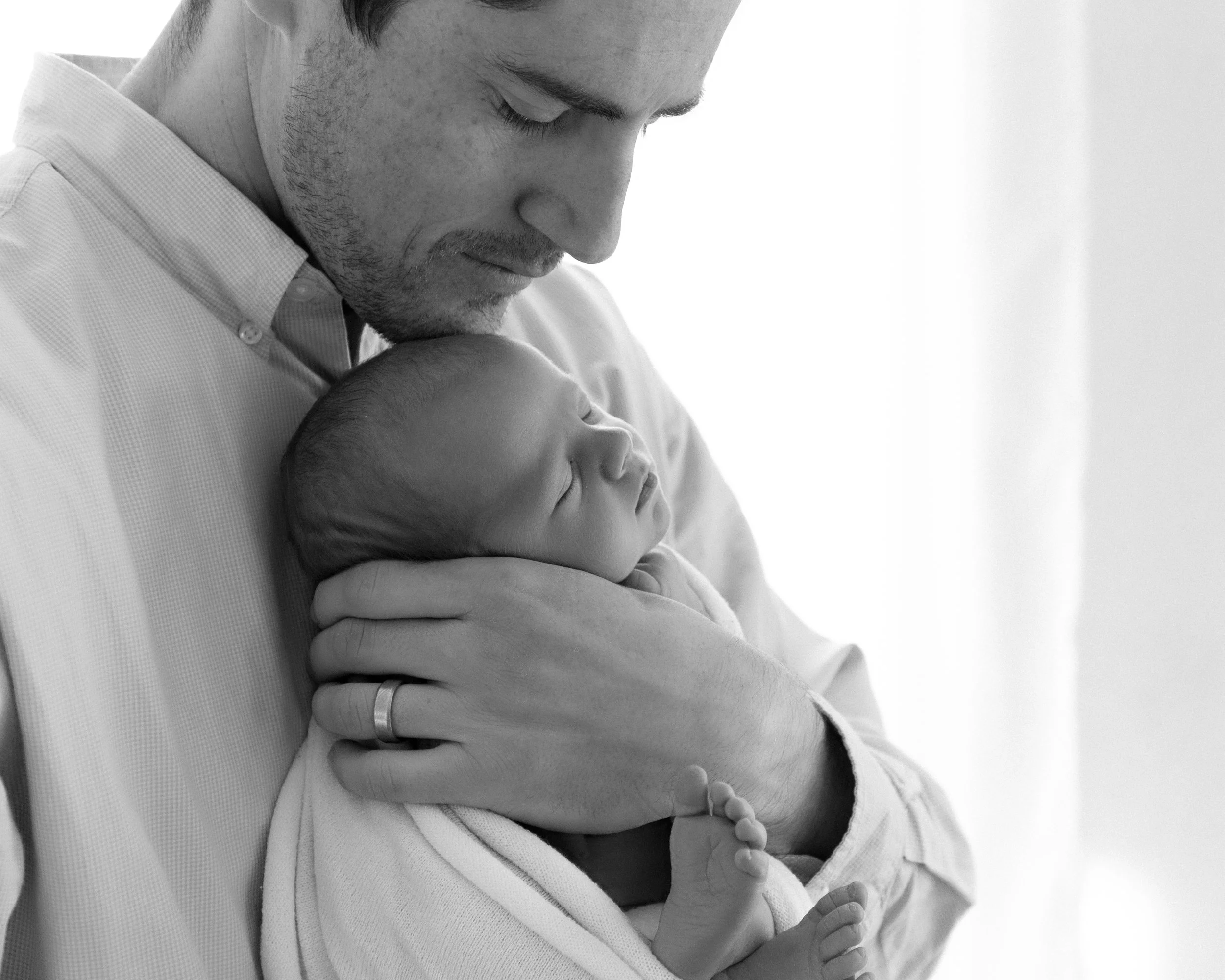 dad holding newborn baby in a photography studio