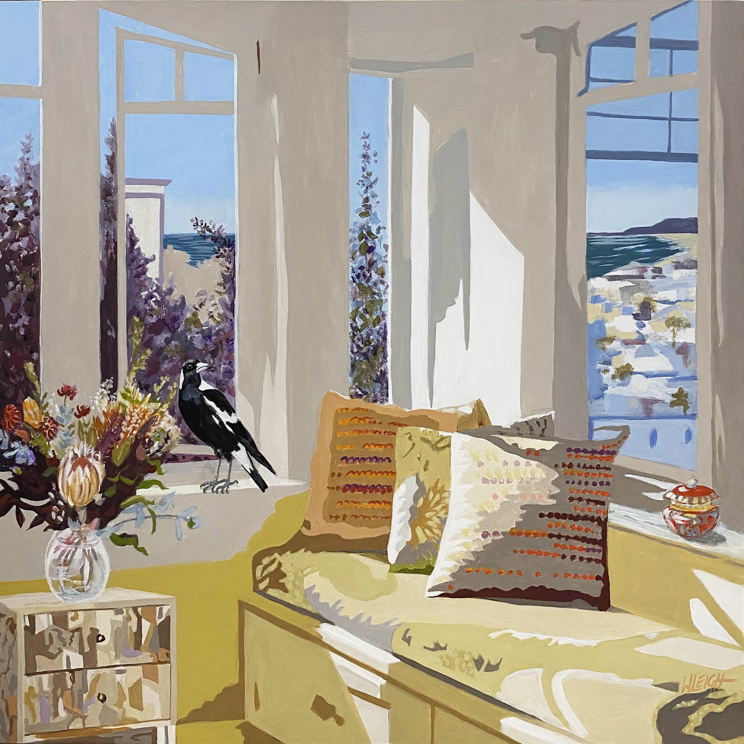 A cozy room with a window seat, colorful pillows, a vase of flowers, and a bird on the ledge; view of trees and ocean outside.