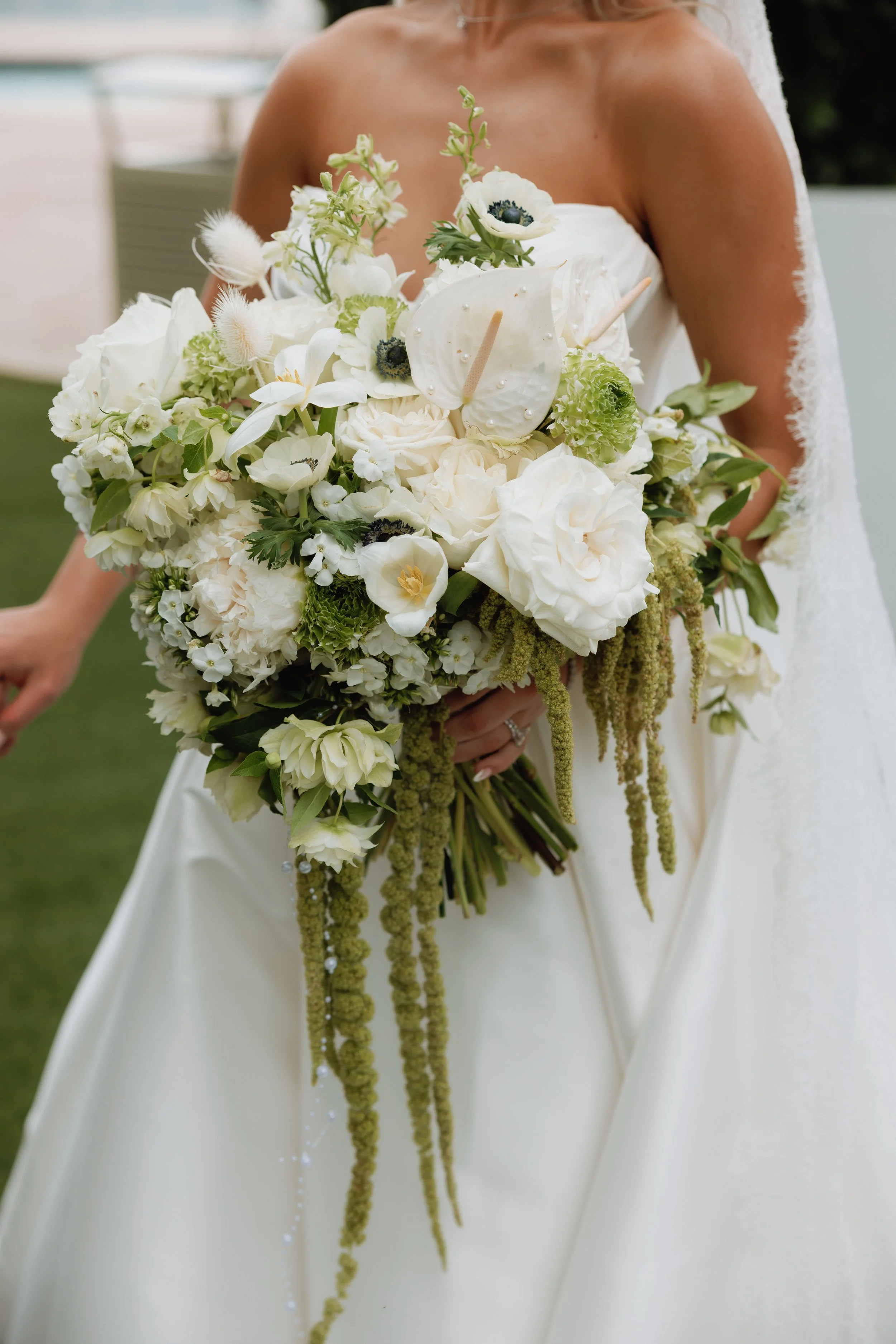 A dreamy white and green bridal bouquet filled with lush roses, delicate anemones, textured blooms, and cascading greenery. A beautiful inspiration for an elegant, romantic, garden-inspired wedding.
