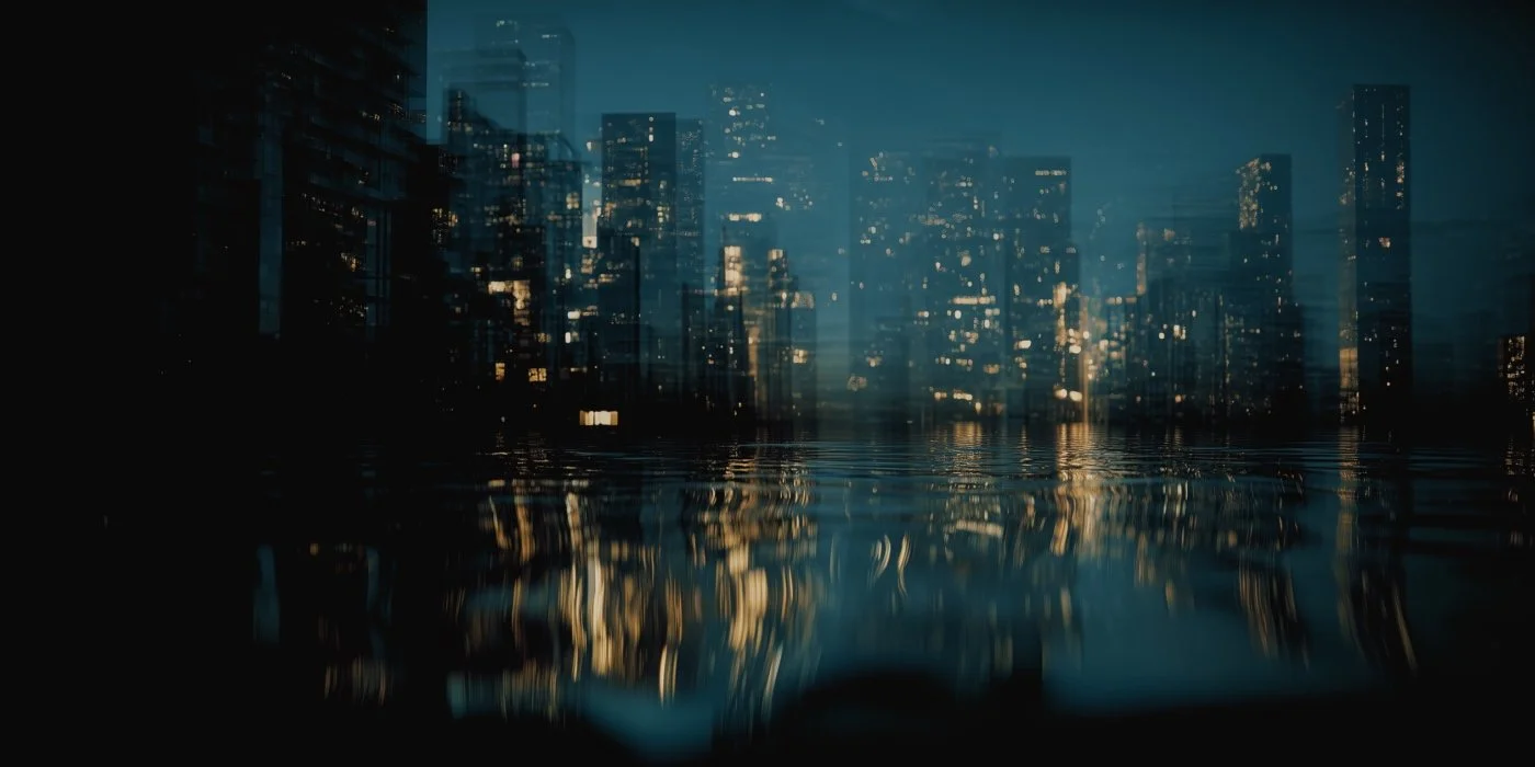 Nighttime city skyline reflected in water with tall buildings and lit windows.