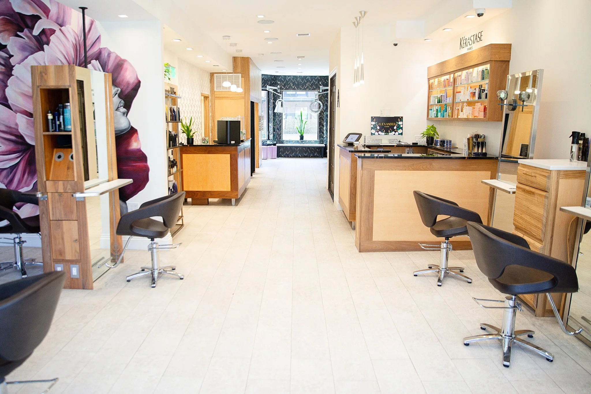 view of interior of salon with stations and front desk and mural