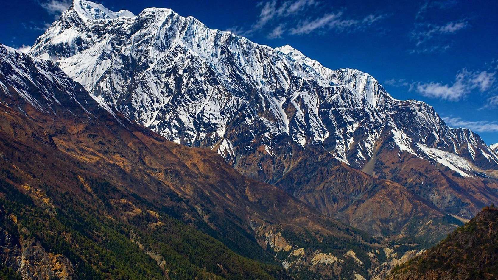Snow-capped mountain with rugged slopes and clear blue sky.