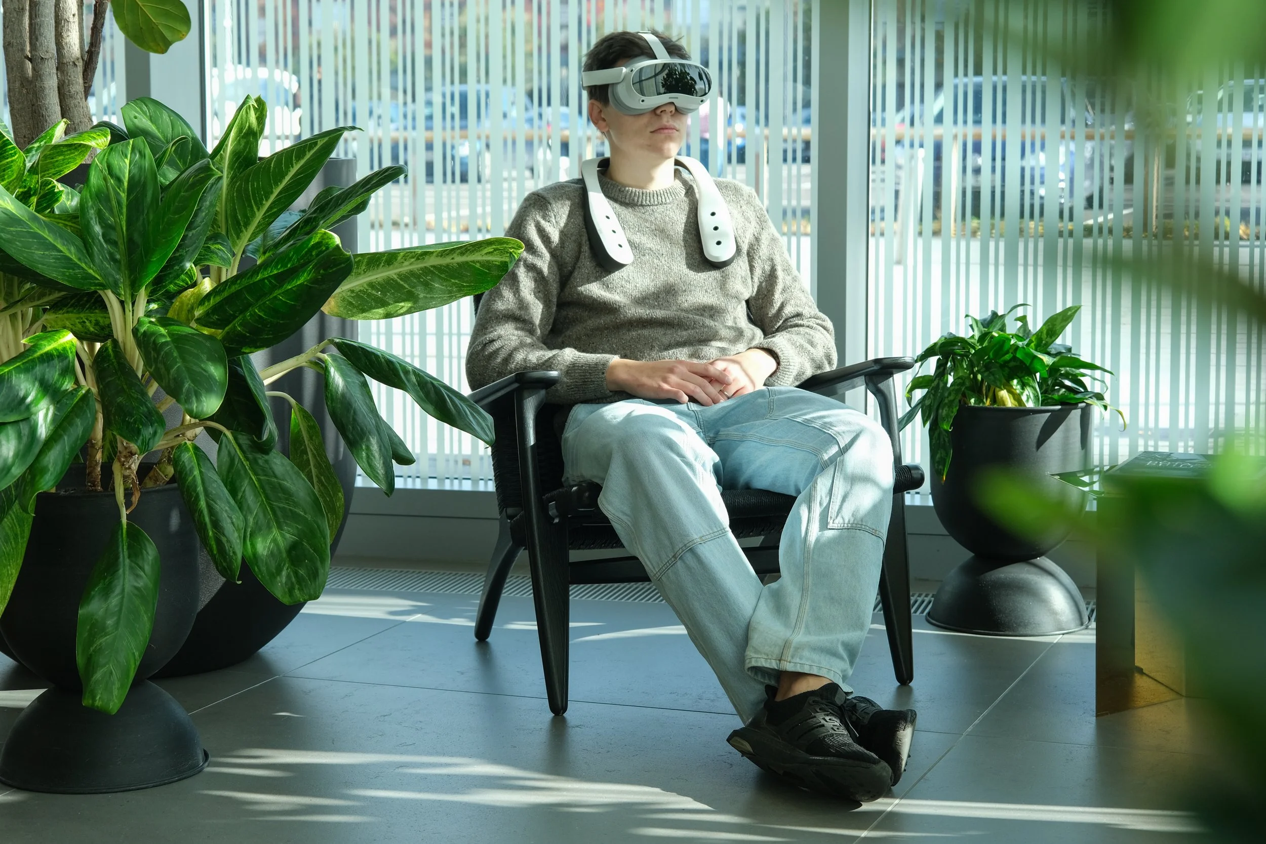 Person sitting in a chair using a VR headset and scent device. Immersive multisensory experience with scent.