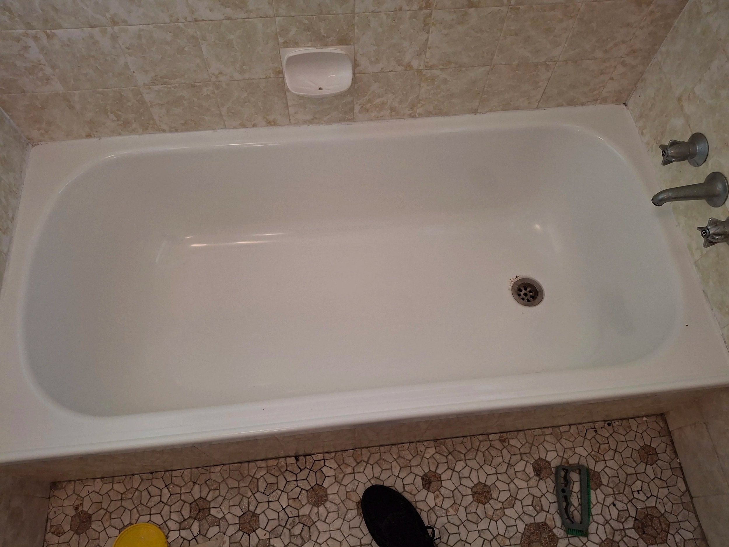 An "after" photo showing a clean bathtub, visibly white & shiny. A reflection can be seen in the tub.