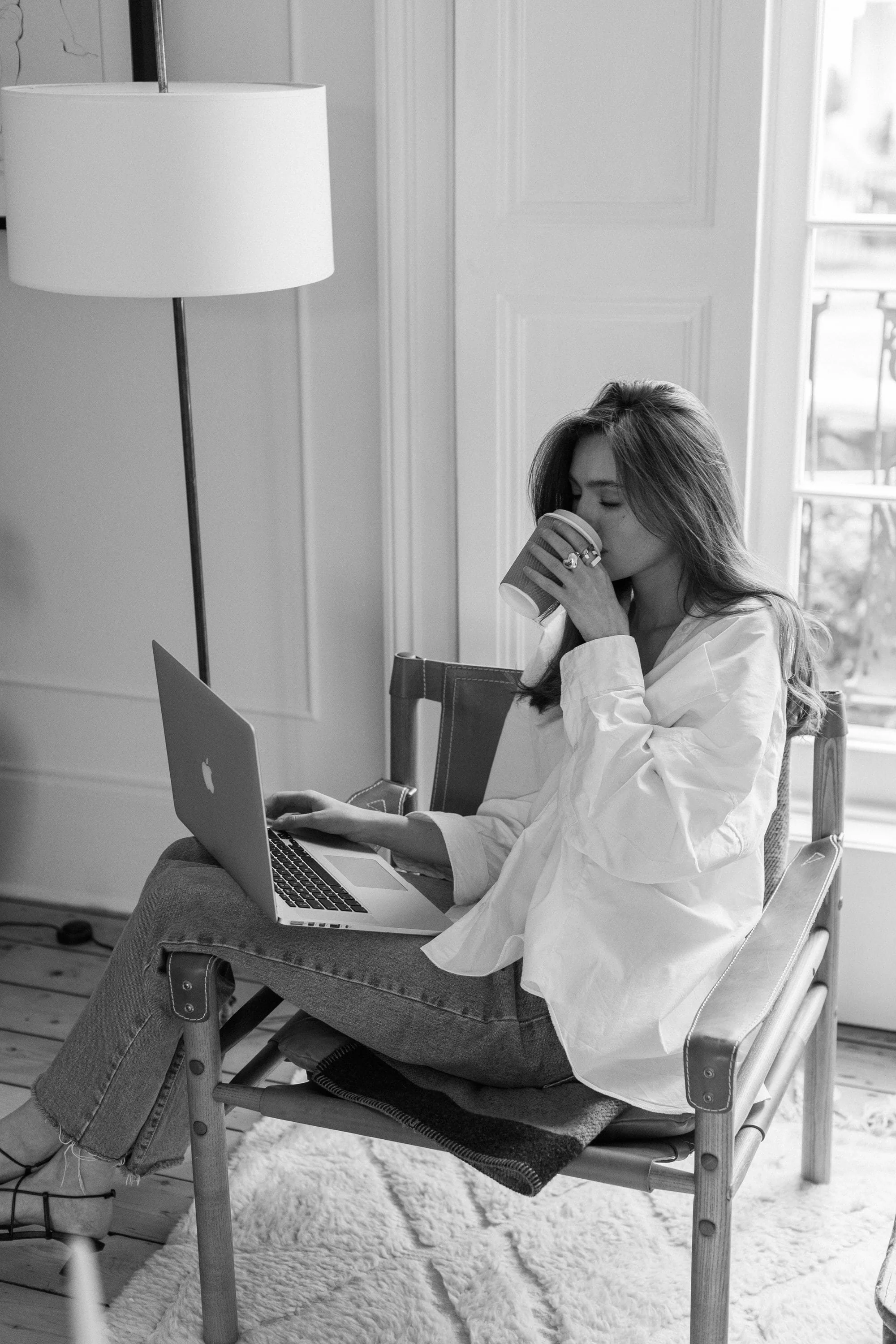 Woman sipping coffee while working on laptop