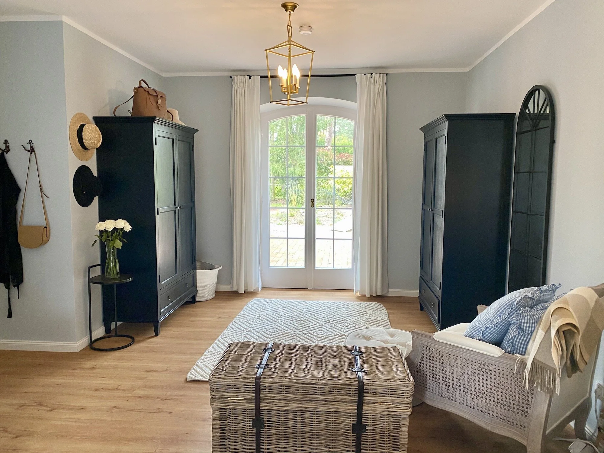blue bedroom in country style with wicker chest, black wardrobes and Loberon armchair.jpeg