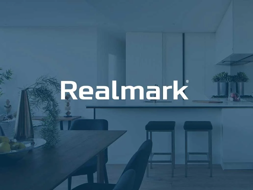 Modern kitchen and dining area with the Realmark logo in the center.