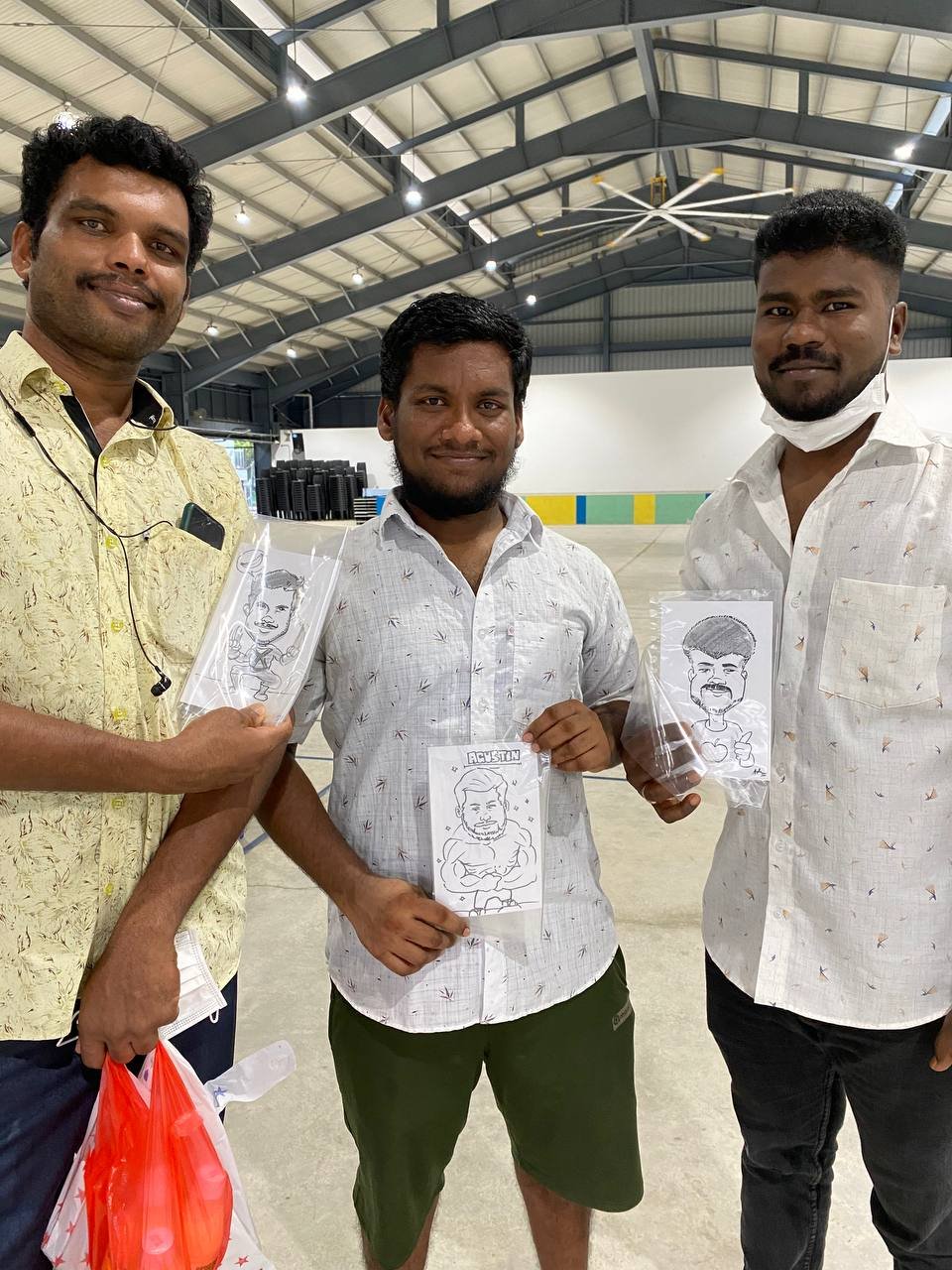 Migrant workers holding caricature drawings at Cochrane RC 5.jpeg