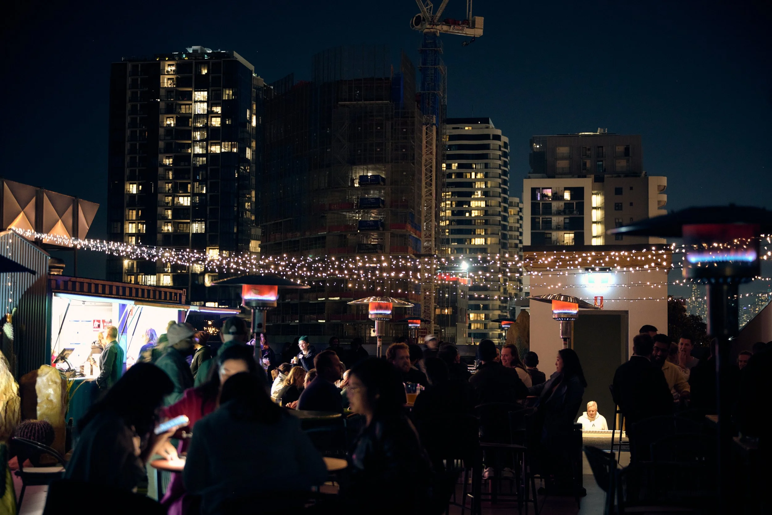 rooftop at moon dog wild west is lit up by fairy lights and the backdrop of the city. the bar is open on busy nights. just another space available to patrons in this huge venue.