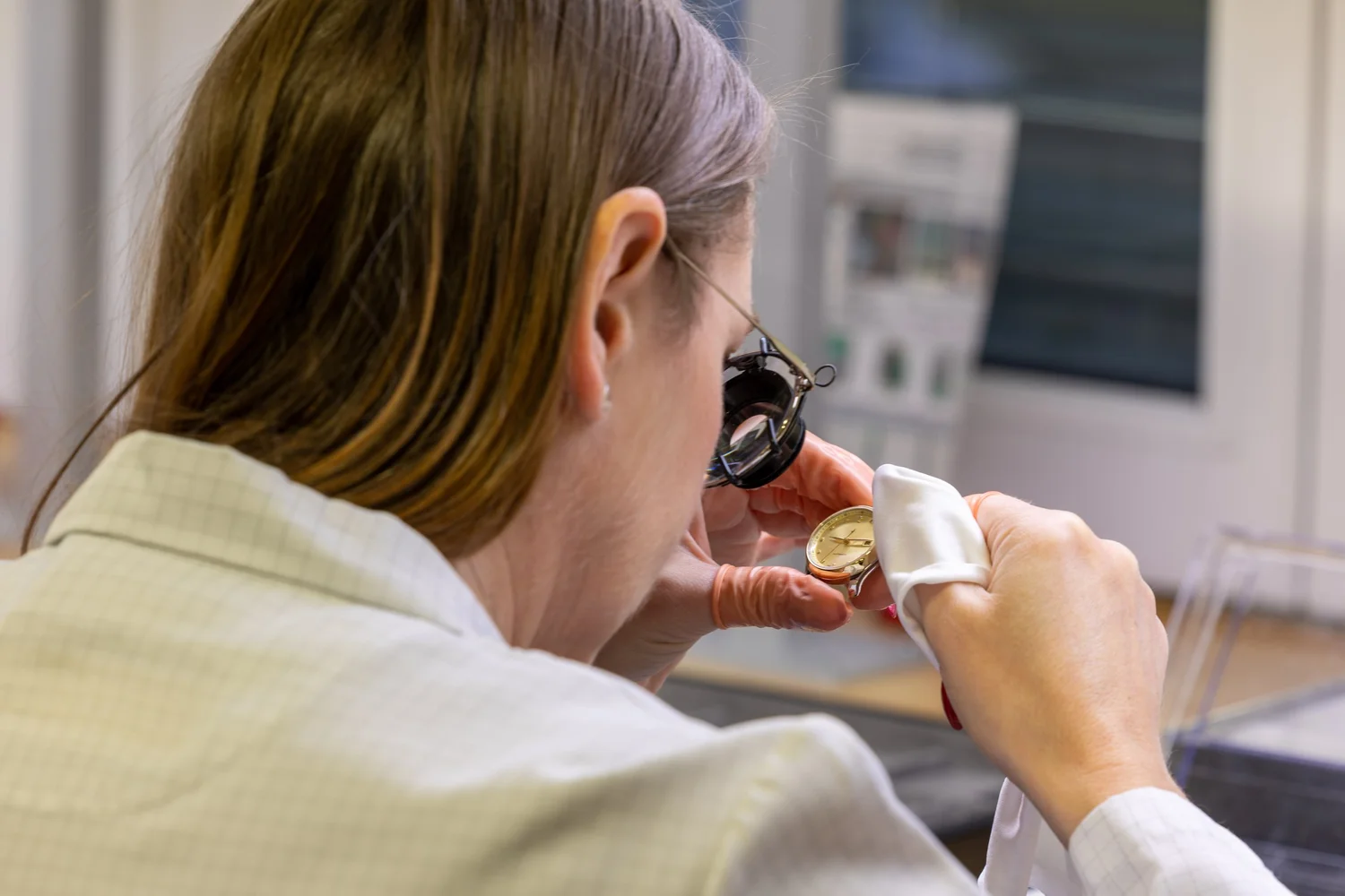 Swiss watchmaker inspecting a watch under a loupe during OEM quality control