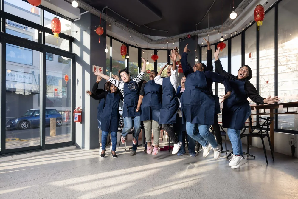 HOME.BAO owner Tina and her employees  jump for joy in her restaurant in Cape Town.jpeg
