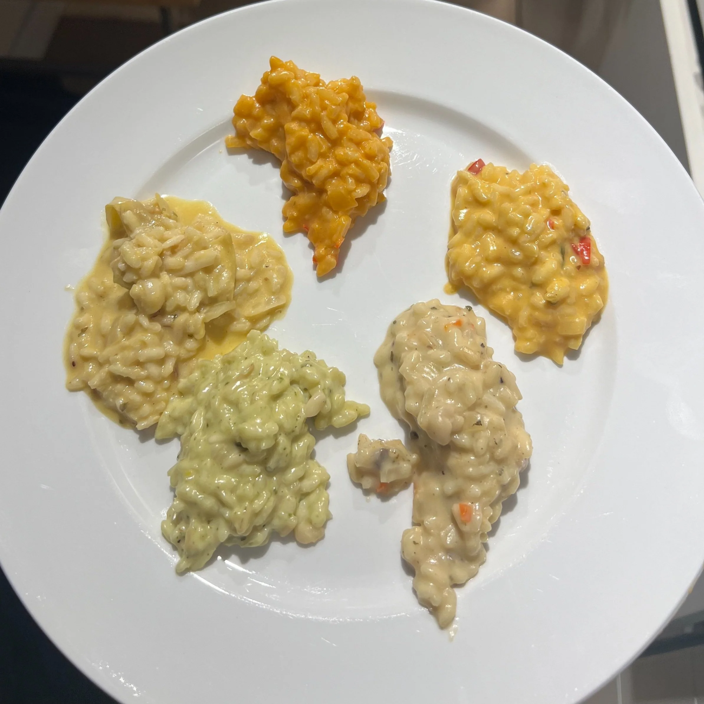 Five different types of risotto on a plate.