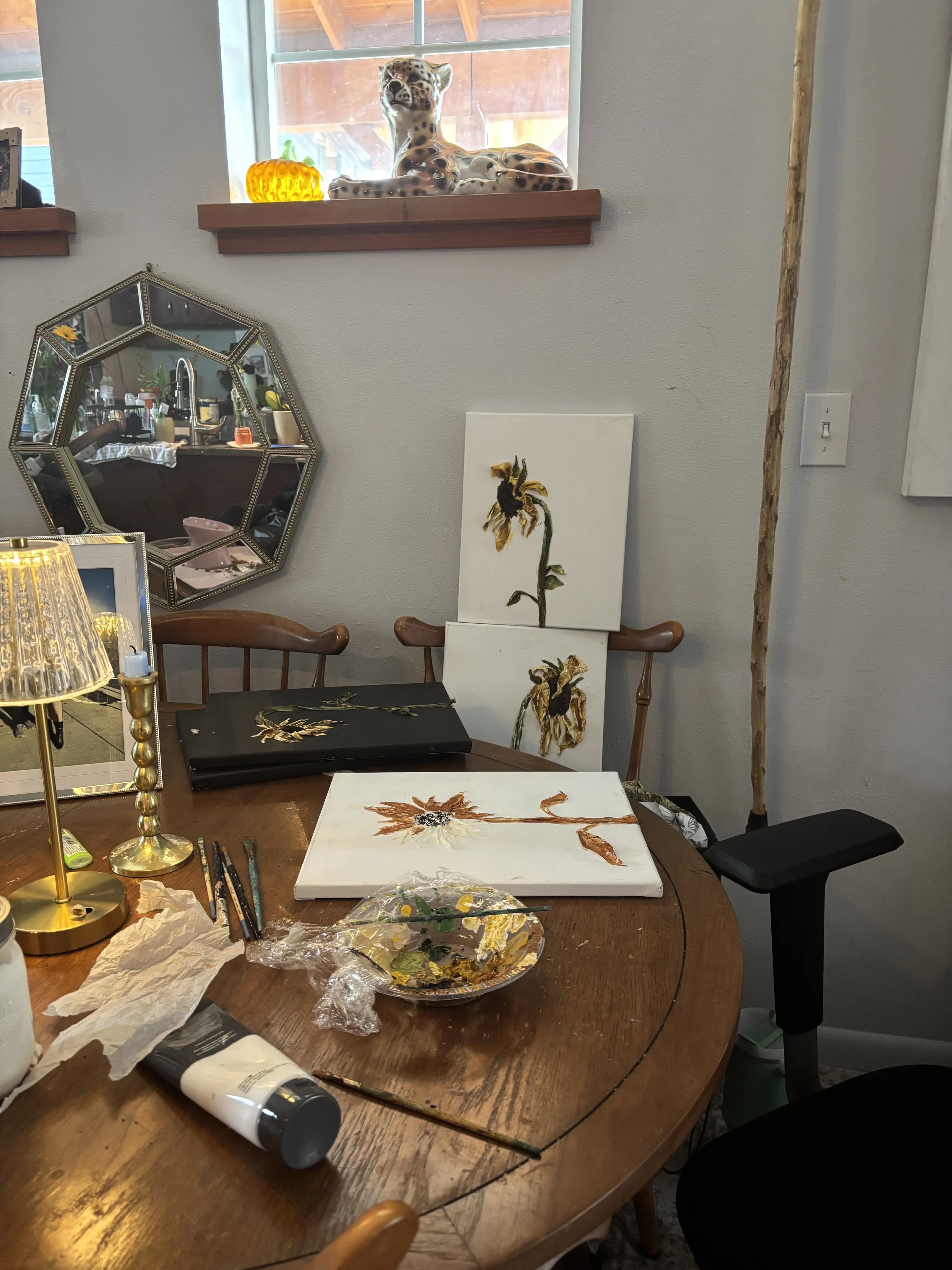 artist working on sunflower painting at dining table, mixed media process