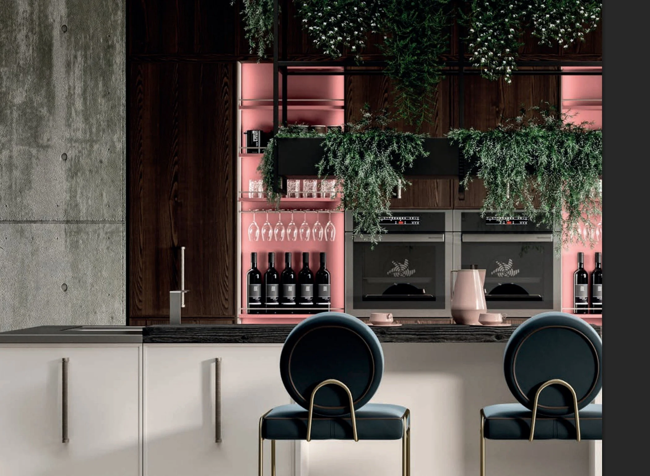 Modern kitchen with dark wood cabinets, pink shelving, hanging wine glasses, bottles of wine, a double oven, and a marble countertop with a pink jug, cups, and greenery.