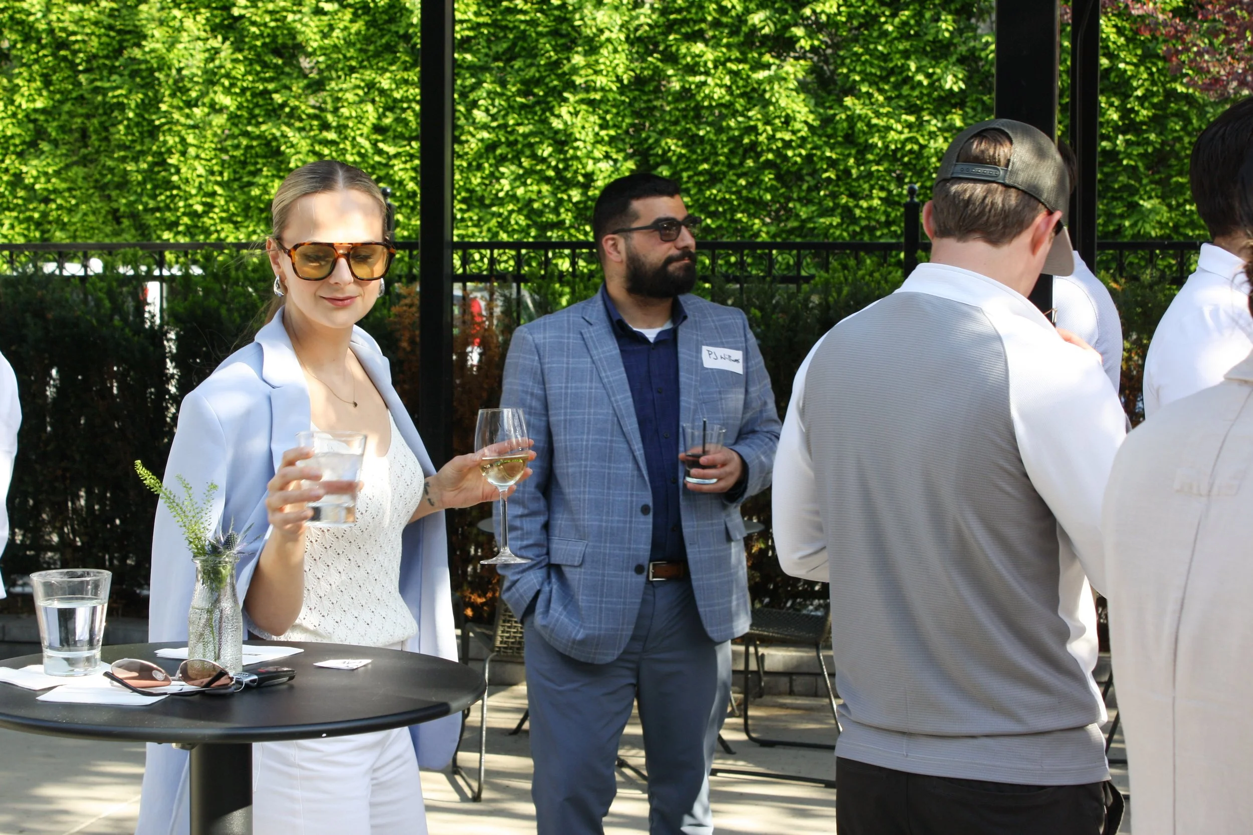 A guest sets their drink down on a cocktail table at an outdoor happy hour on the patio of High Line Car House, a historic industrial event venue in Columbus, OH.