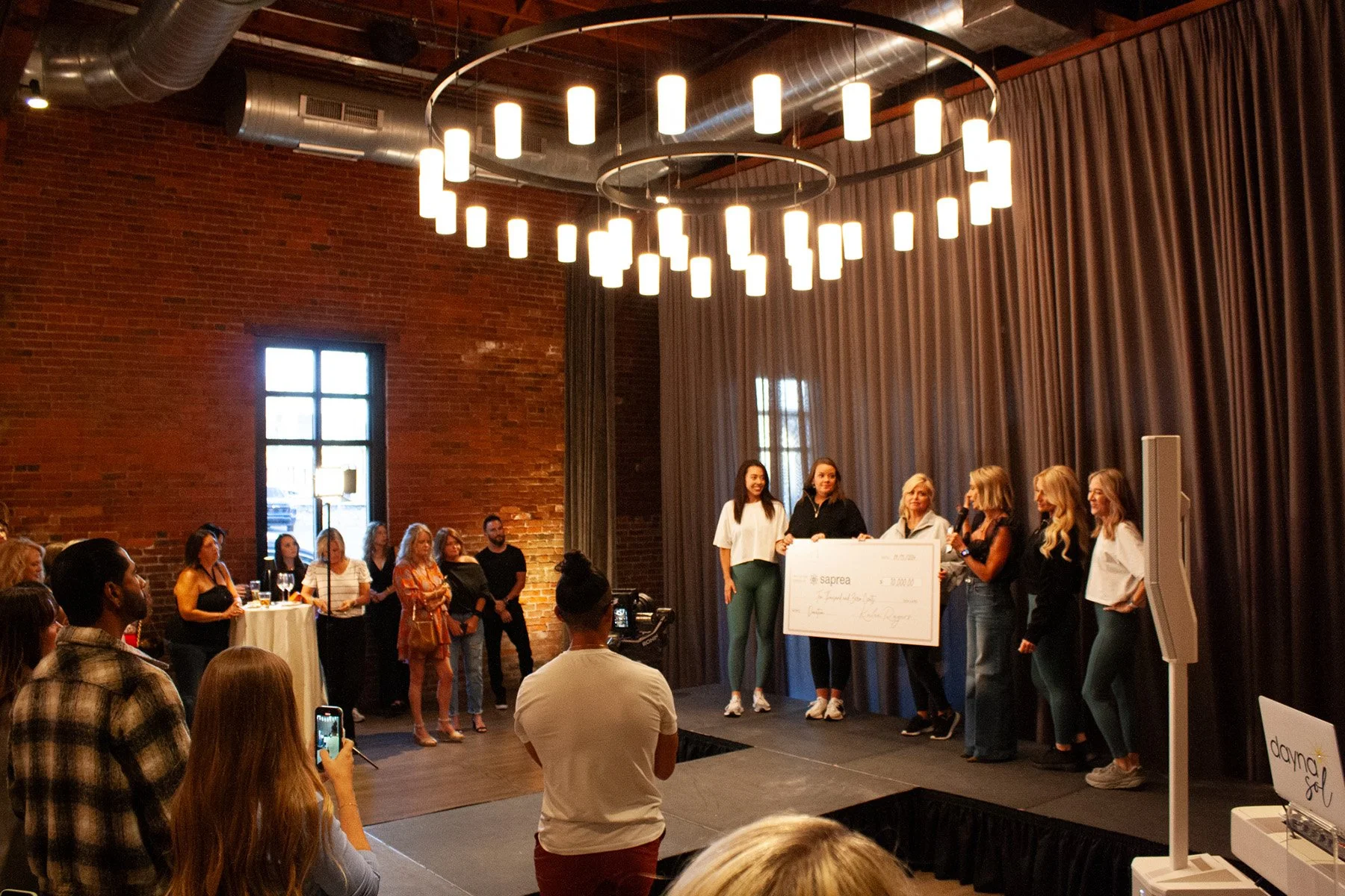 A group of women hold a check on a runway stage at High Line Car House, an event venue in Columbus, Ohio
