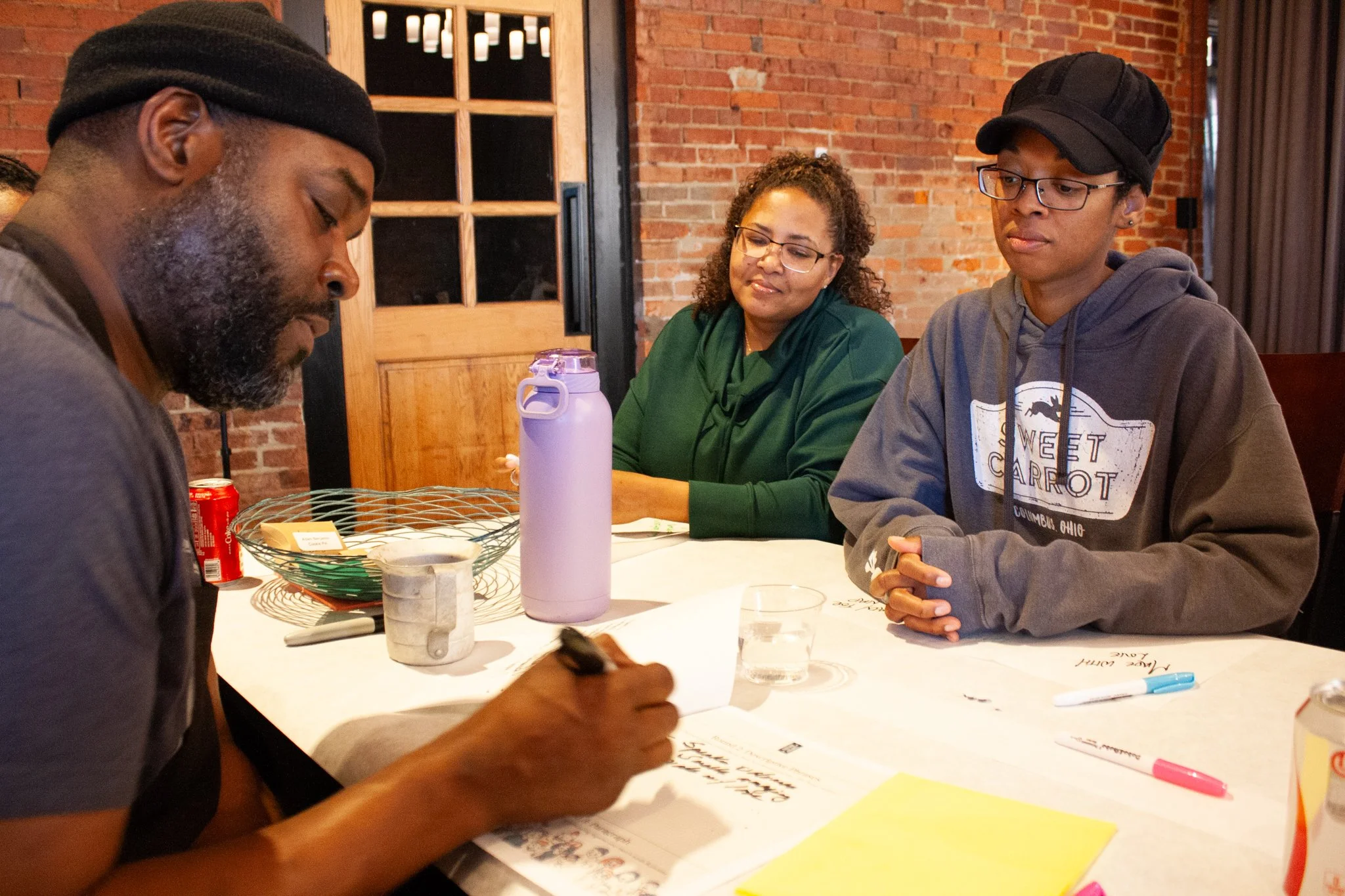 Three coworkers sit together to brainstorm during a team meeting in a historic event space in downtown Columbus Ohio.