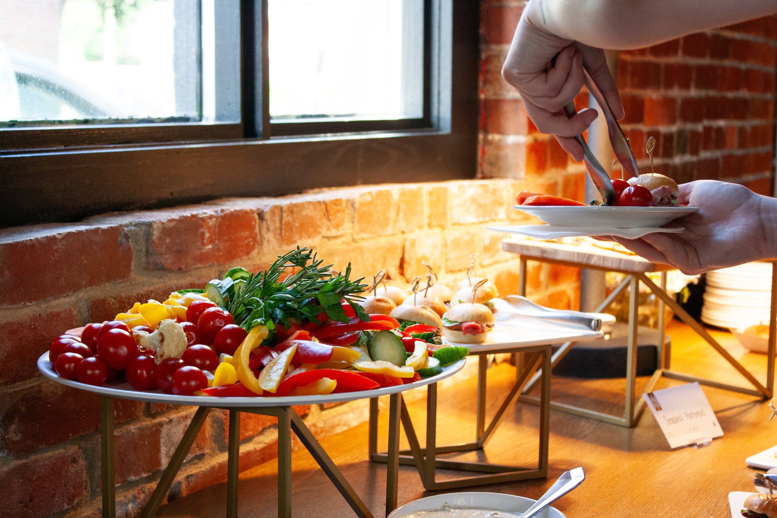 A crudité veggie display is set up at a corporate happy hour in Columbus, Ohio. A guest is adding some veggies to their plate.