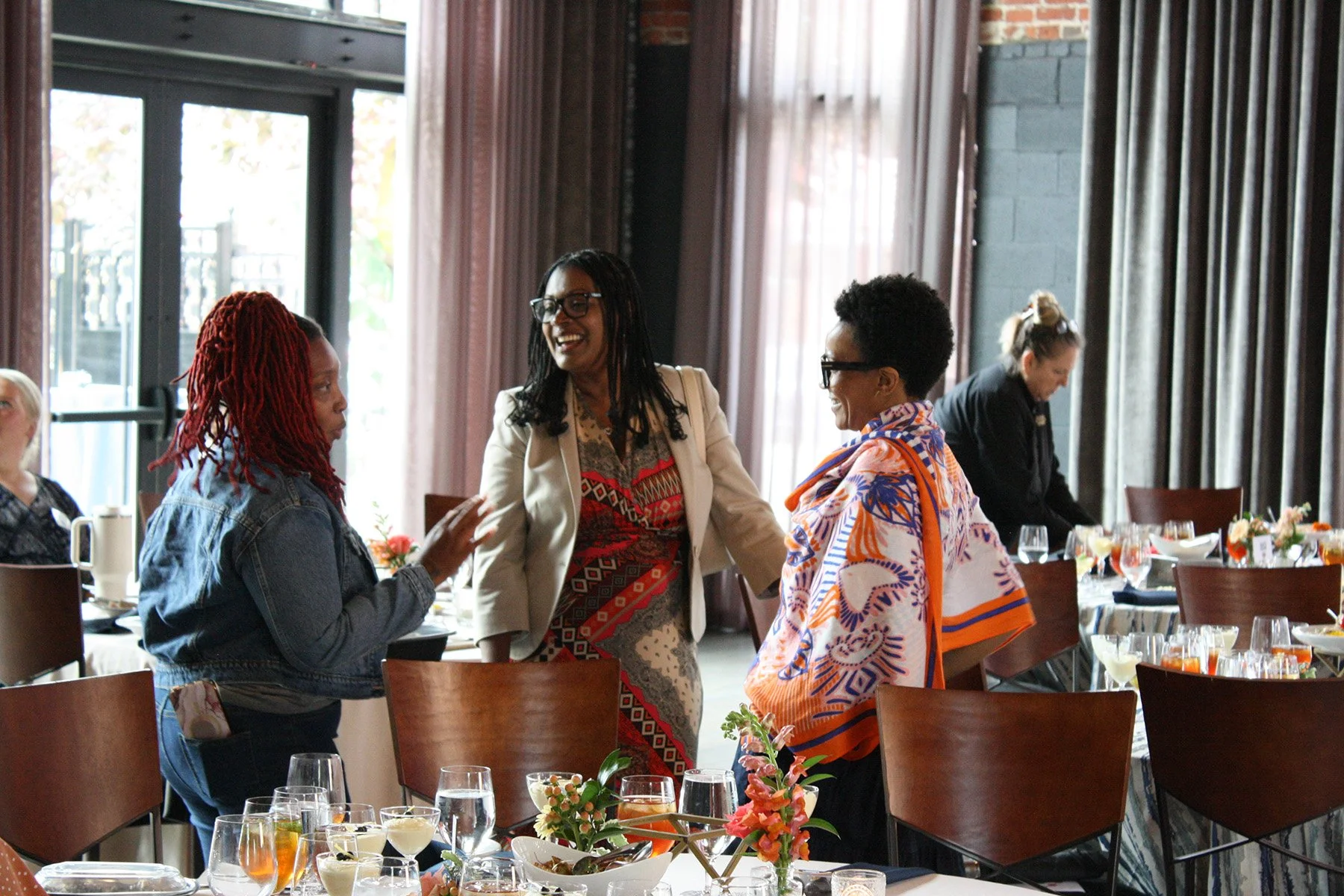 Three guests chat while standing next to their table at a lunch and learn hosted at an event space in Columbus, Ohio.