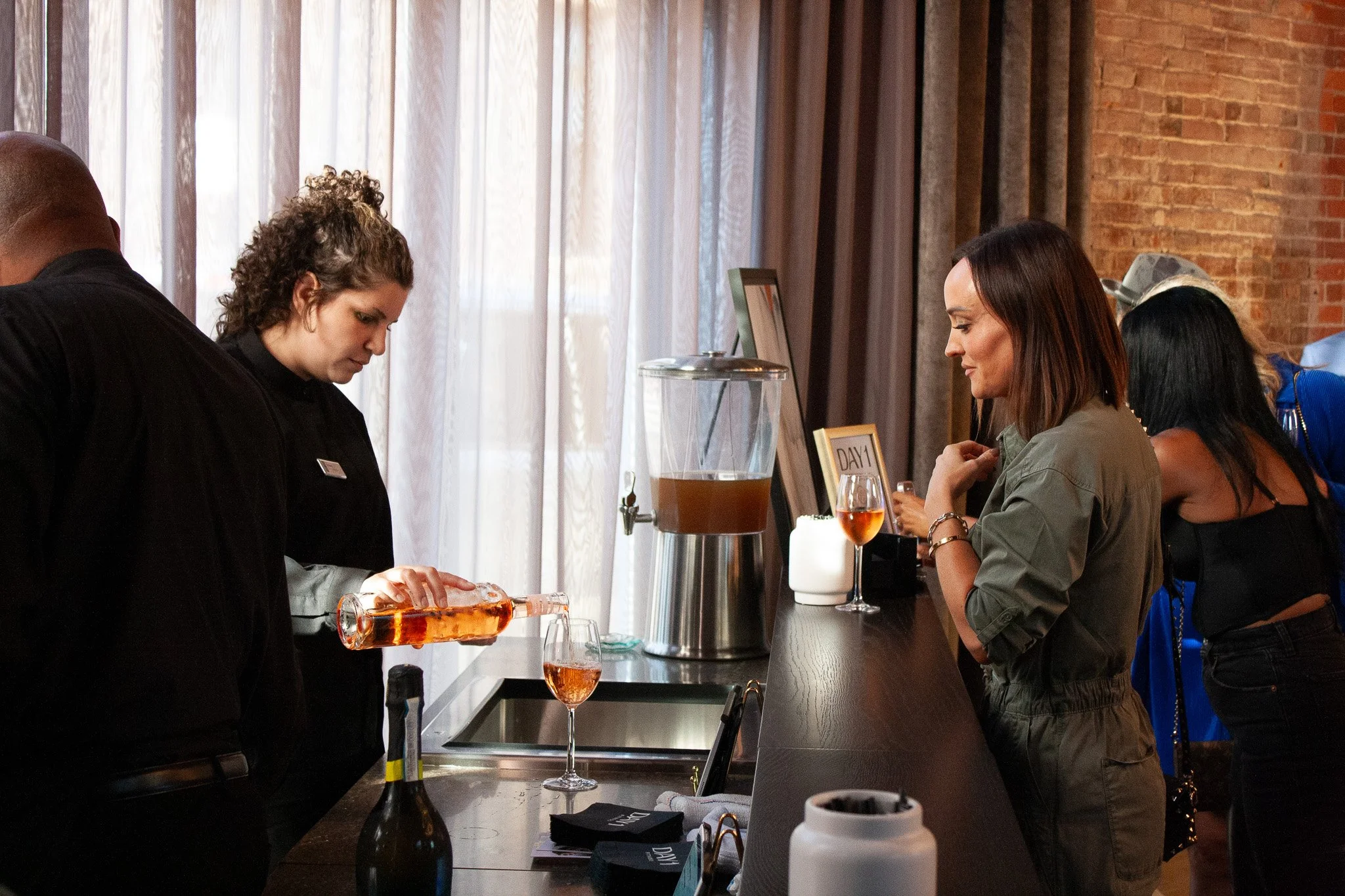 A bartender pours a glass of rose for a guest at a social event in an industrial event venue in Columbus, Ohio