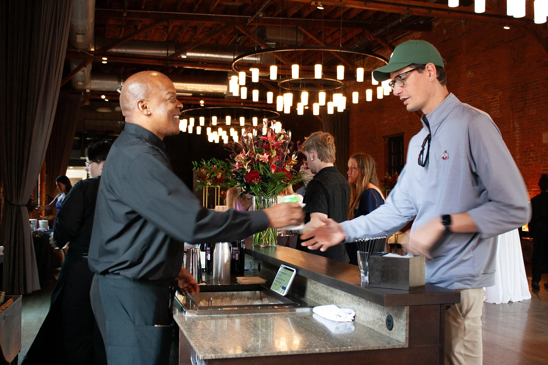 A bartender serves a guest a drink with a smile at a large event venue in downtown Columbus, OH.