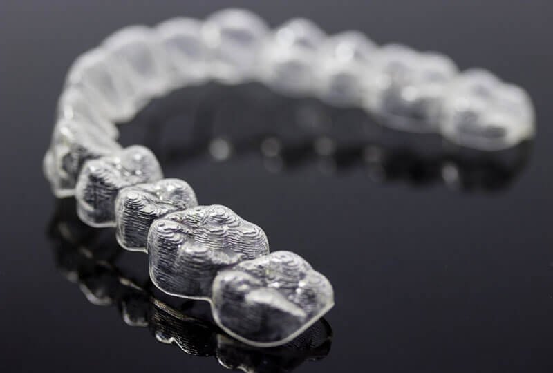 Invisalign clear aligner trays on a black background