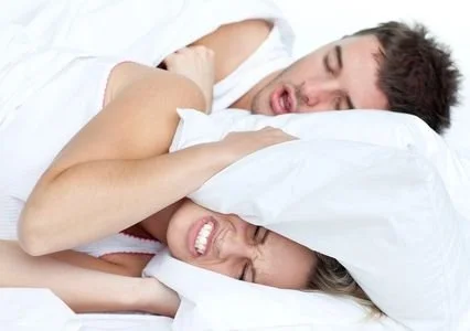 Couple sleeping with husband snoring and wife angry in bed