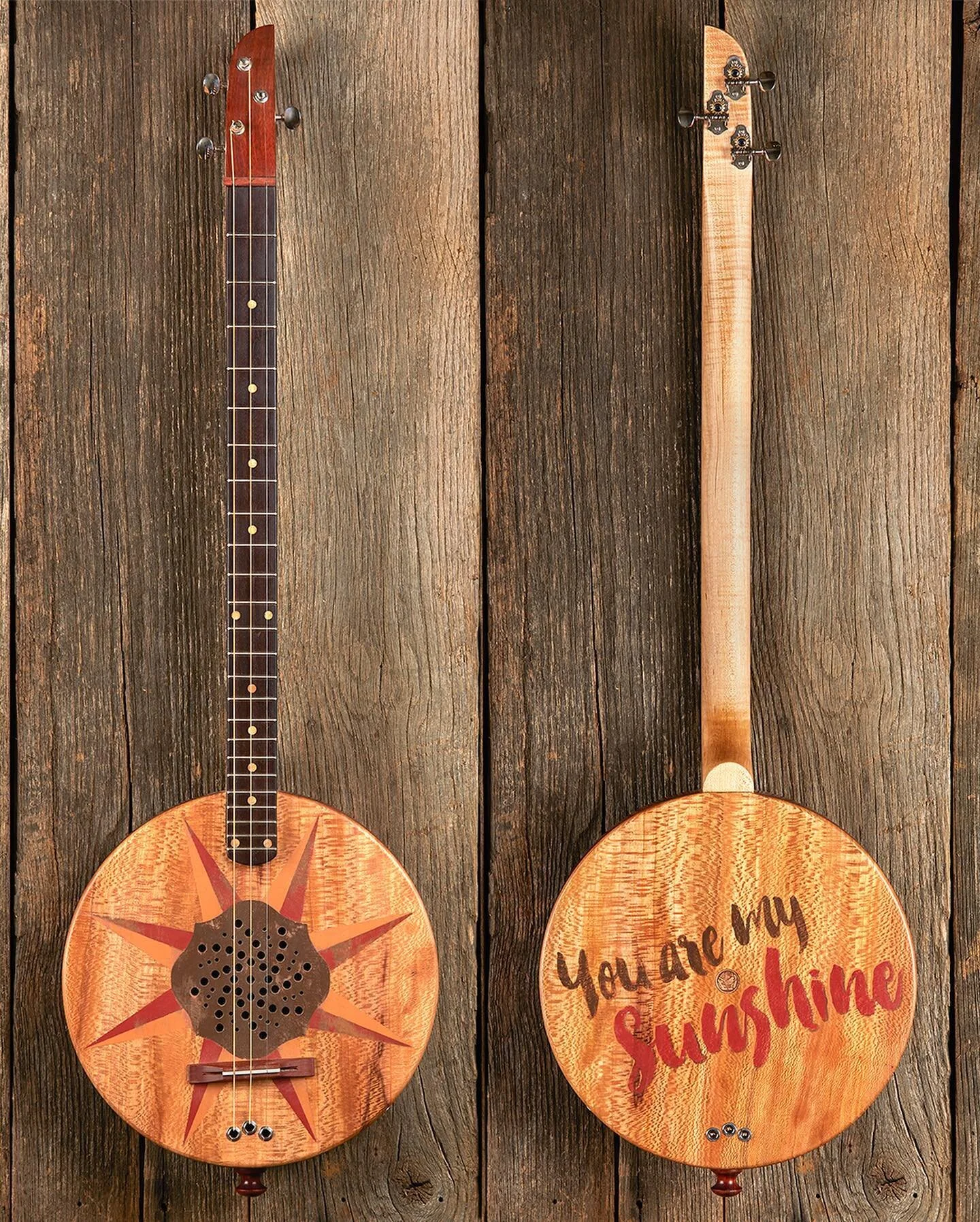 A three string, acoustic/electric guitar that features a painted sycamore top and back, with a hard rock maple neck and a Mexican ebony fretboard. The body is bloodwood with walnut dots and the bridge is bloodwood with antique ivory. A copper Haitian