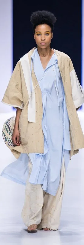 Model on runway wearing layers of loose, pastel garments