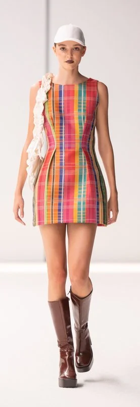 Model in a colorful plaid dress with white cap and brown boots