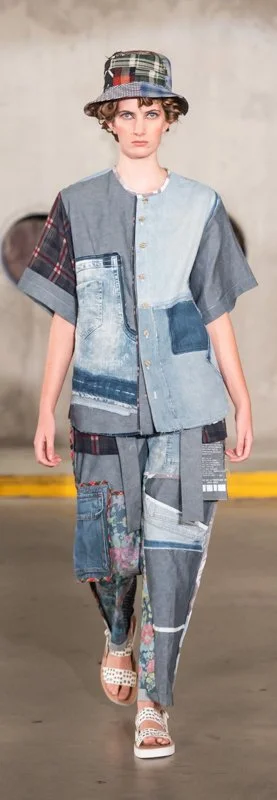 Model wearing patchwork denim outfit with matching bucket hat on runway