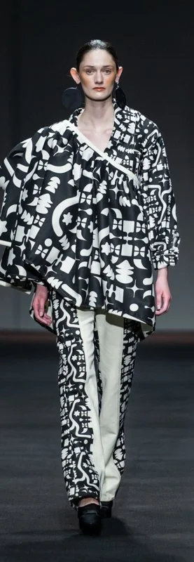 Model on runway wearing black and white abstract patterned outfit and asymmetrical black shoes.