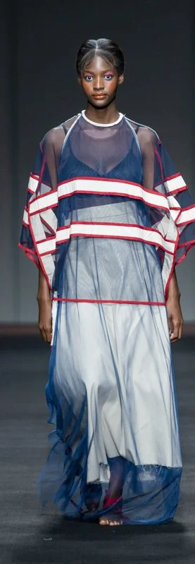 Model on runway in sheer blue and red striped dress