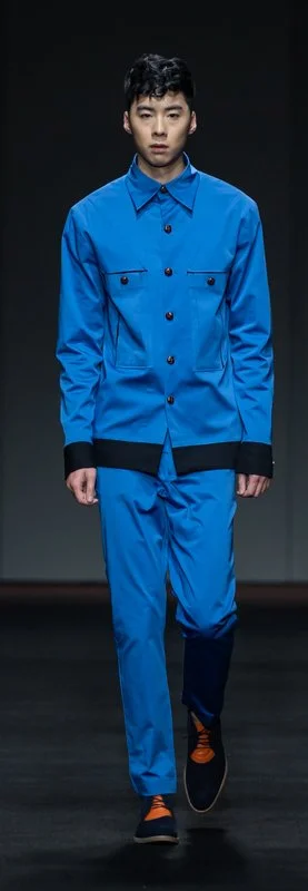Model wearing a blue outfit with black accents on a fashion runway.