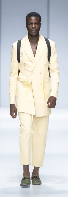 Male model wears a light yellow suit with cropped pants on a runway.
