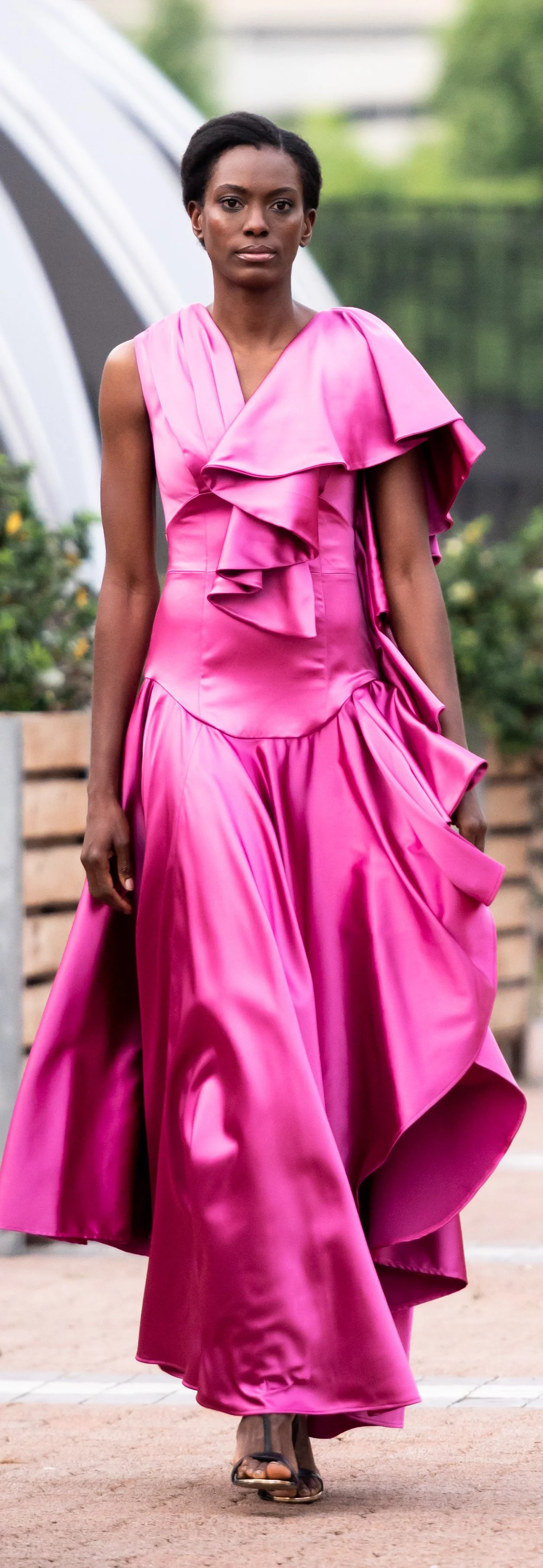 Model in flowing pink dress walking outdoors